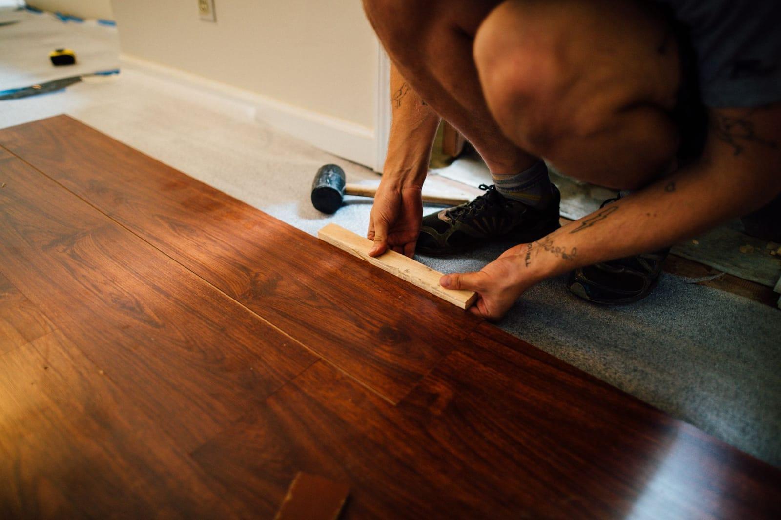 Installer fitting wide-plank wood flooring in a home