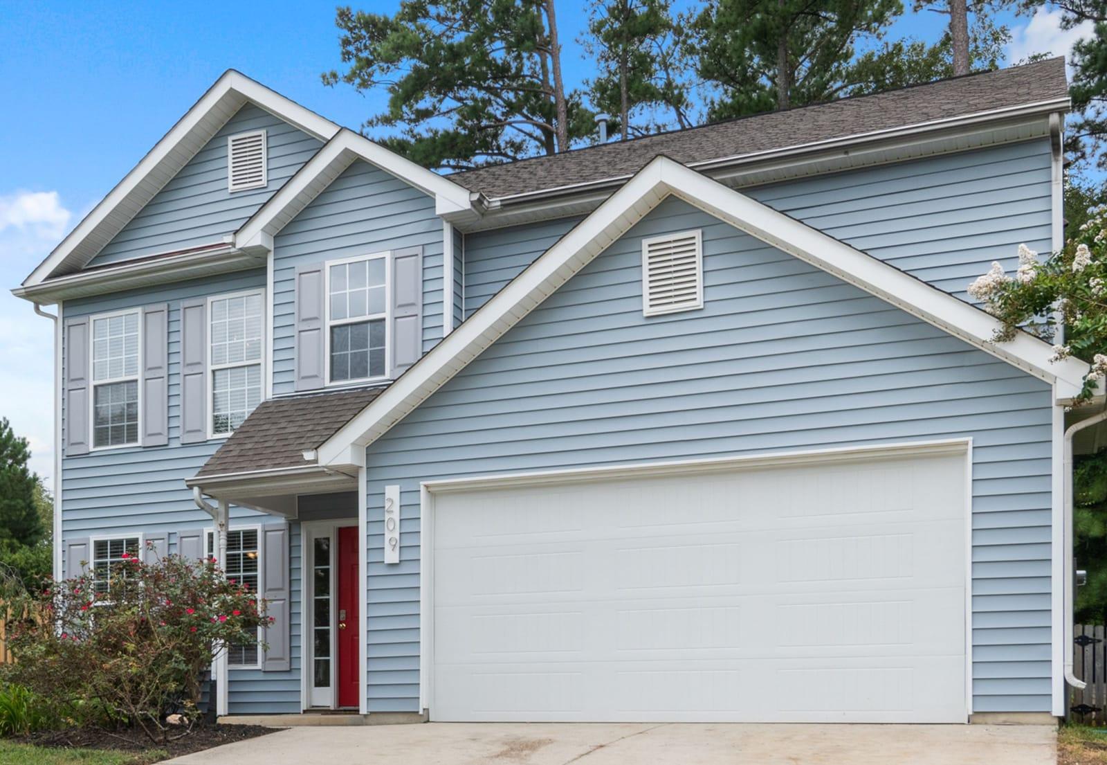 Two-story home clad in blue lap siding with white trim and gable vents